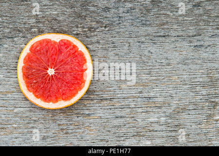 Pink ripe grapefruit slice on old wooden background Stock Photo