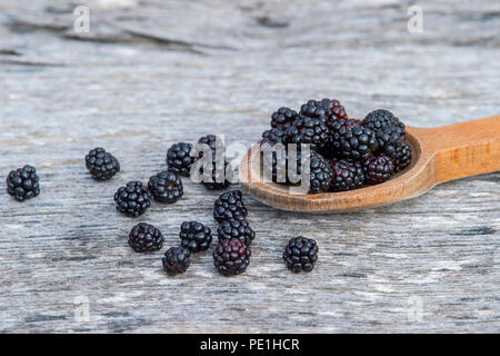 Ripe blackberries in wooden spoon on old wooden background Stock Photo