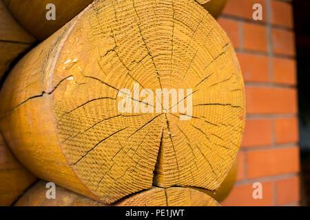 Wooden log house closeup with red brick wall background Stock Photo