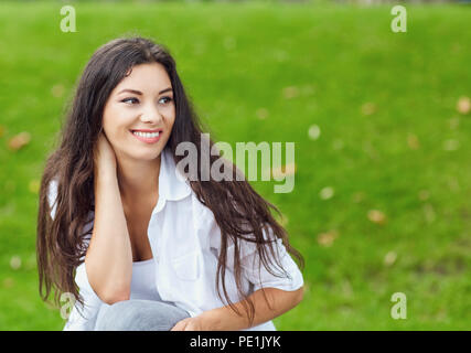 Beautiful happy brunette woman smiling on green grass outside ba Stock Photo