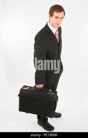 Side full body view of a man in black suit pants and black shoes holding a briefcase in the right hand on white background. Stock Photo