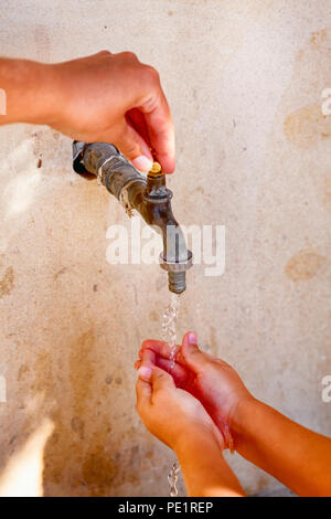 Woman hand open water tap and child washing his hands. Close up. Stock Photo