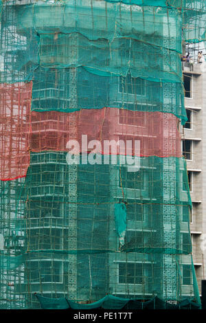 Bamboo scaffolding and meshing on exterior of high rise apartment building under construction in Mumbai, India Stock Photo