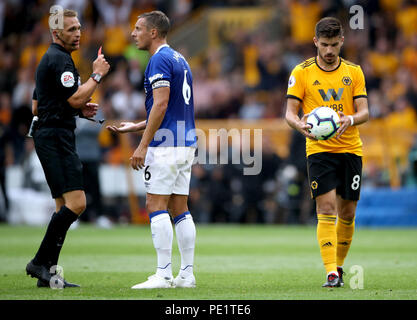 Referee Craig Pawson shows a red card to Everton's Phil Jagielka after a tackle on Wolverhampton Wanderers' Diogo Jota (not in picture) as Ruben Neves (right) lines up to take a free kick during the Premier League match at Molineux, Wolverhampton. Stock Photo