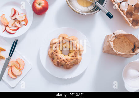 Traditional apple pie near ingredients and utensils on white table, top view. Flat lay homemade bakery food composition. Stock Photo