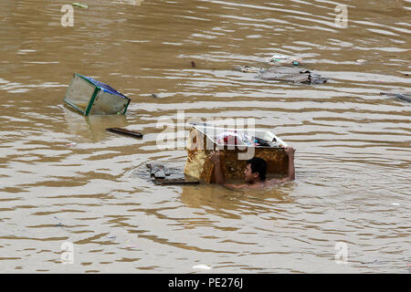 Marikina City, Philippines. 12th Aug, 2018. A resident holds on to a box full of his belongings as he swims through the flood brought by tropical storm Yagi in Marikina City, the Philippines, Aug. 12, 2018. Credit: Rouelle Umali/Xinhua/Alamy Live News Stock Photo