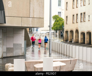 Holyrood, Edinburgh, Scotland, United Kingdom, 12th August 2018. UK Weather: the rain and mist as the remnants of Storm Debby hits the capital does not deter joggers running at the Scottish Parliament building at the bottom of Canongate on the Royal Mile Stock Photo