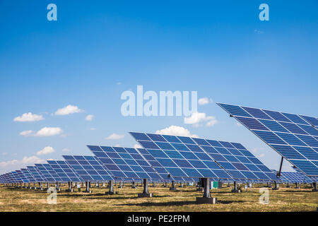 Group of solar panels on a blue sky with clouds. Concept of solar energy. Side view. Stock Photo