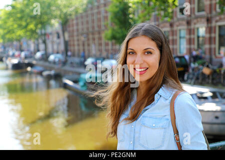 Smiling urban girl on bridge looking at camera. Young beautiful woman wearing casual jeans shirt in Amsterdam, Netherlands. Stock Photo