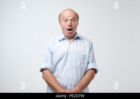Wow concept. Attractive male half-length front portrait. Senior emotional surprised man standing with opened a little mouth. Human emotions, facial ex Stock Photo