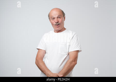 Wow concept. Attractive male half-length front portrait. Senior emotional surprised man standing with opened a little mouth. Human emotions, facial ex Stock Photo