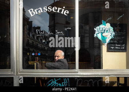 An older man sitting alone in a brasserie in Paris, France Stock Photo