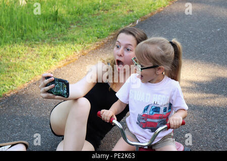 Two making silly faces and taking cell phone selfies Stock Photo