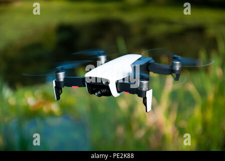 White drone flying near small lake Stock Photo