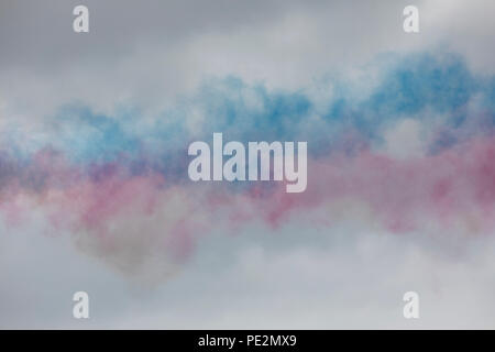 Coloured smoke lingering in the air after a Red Arrows flypast Stock Photo
