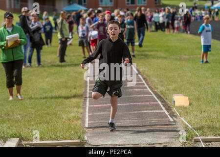 Young boy competing in track & field's  trple jump, wearing hoodie and shorts. Determinded look as he prpares to take jump. Model released Stock Photo