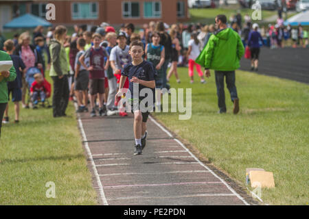 Young boy competing in track & field's  trple jump, wearing t-shirt and shorts. Determinded look as he runs to take jump. Model released Stock Photo