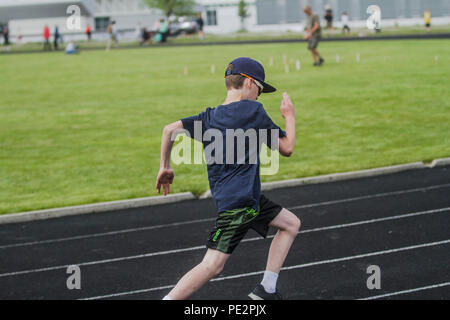 Young boy competing in track & field's, distance race, wearing shorts, t-shirt, hat and sunglasses.. Model released Stock Photo