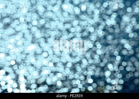 Chaotic movement of small numerous defocused light spots. Sunlight is reflected in the waves running along the shore. Fancy water color Stock Photo