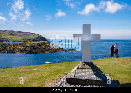 The Thousla Cross at southern tip on coast overlooking Calf of Man island with two people looking out to sea. Kitterland Isle of Man British Isles Stock Photo