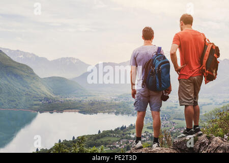 friends hiking in Europe, hike in Alps in Annecy, France, outdoor summer activity with backpack, two people backpackers standing on top of mountain an Stock Photo