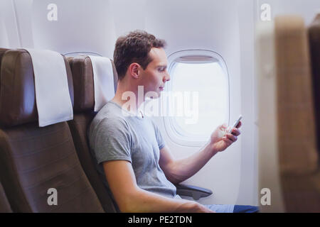 passenger of airplane using mobile smart phone in the plane, travel app on smartphone Stock Photo