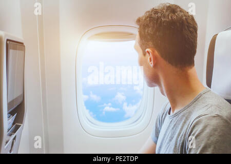 passenger of airplane looking at window, international travel, happy man tourist enjoy flight in comfortable air plane Stock Photo