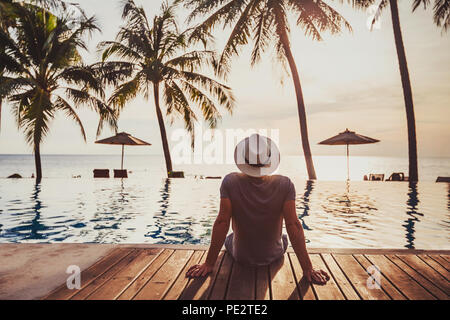tourist in luxury beach hotel near luxurious swimming pool at sunset, tropical exotic holidays vacation, tourism and travel