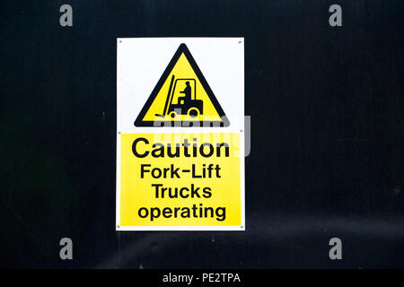 Fork lift trucks operating caution sign yellow and white on black background Stock Photo