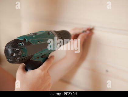 Close-up the woman holding the screw and the electric screw-driver. Stock Photo