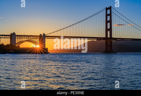 Starburst effect on the sun setting behind the famous Golden Gate Bridge in San Francisco, California Stock Photo