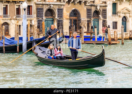 Venice, Italy - September 23, 2017: Gondoliers in traditional stripped shirt rowing a traghetto, cheaper alternative to a gondola, with passengers cro Stock Photo