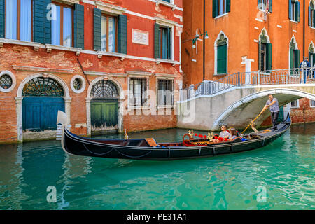 Venice, Italy - September 23, 2017: Gondolas with tourists passing by the picturesque building facades and bridges in one of the canals Stock Photo