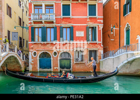 Venice, Italy - September 23, 2017: Gondolas with tourists passing by the picturesque building facades and bridges in one of the canals Stock Photo