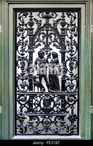 Close up of an ornate metal piece depicting a scene with a man, woman, falcon and a dog on an old door in Stockholm, Sweden Stock Photo
