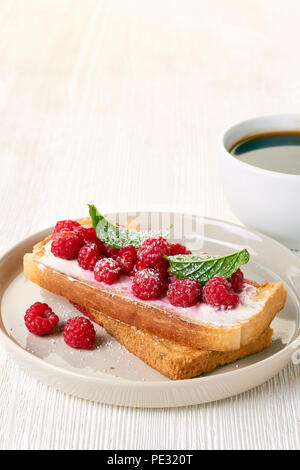 Coffee and toast with fresh raspberries on white table Stock Photo