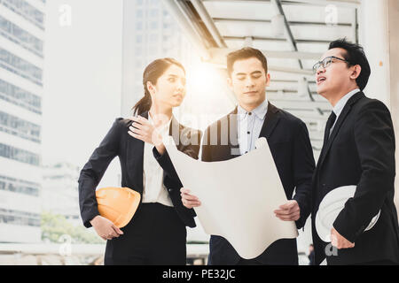 Architecture and engineer explaining project with investor holed blueprint construction in site work. Stock Photo