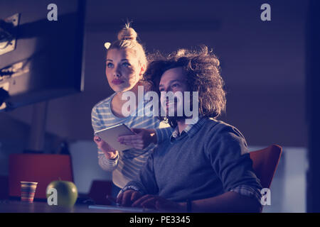 Two young designers are working on a new project in the night office using modern technology Stock Photo