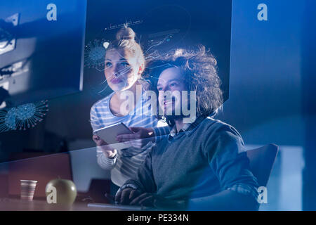 Two young designers are working on a new project in the night office using modern technology Stock Photo