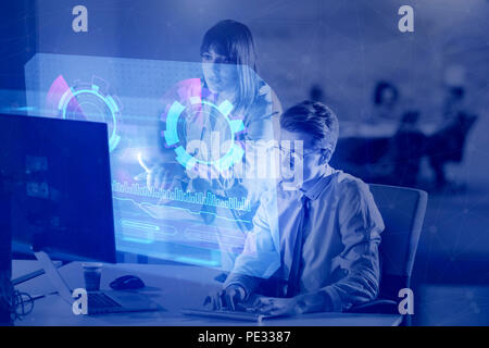 Two young designers are working on a new project in the night office using modern technology with hud display interface Stock Photo