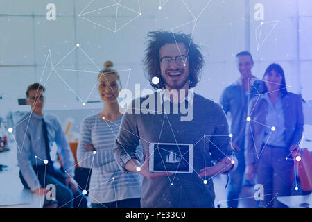 Portrait of a young businessman holding tablet in bright office with colleagues in the background Stock Photo
