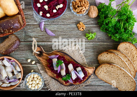 Boiled grated beets, pieces of herring, red onions, nuts on whole grain bread. Delicious and healthy sandwich. Proper nutrition. Top view. Stock Photo