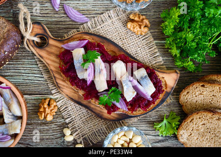 Boiled grated beets, pieces of herring, red onions, nuts on whole grain bread. Delicious and healthy sandwich. Proper nutrition. Top view. Stock Photo
