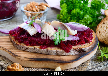 Boiled grated beets, pieces of herring, red onions, nuts on whole grain bread. Delicious and healthy sandwich. Proper nutrition. Stock Photo