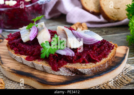 Boiled grated beets, pieces of herring, red onions, nuts on whole grain bread. Delicious and healthy sandwich. Proper nutrition. Stock Photo