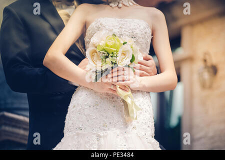 Bride and groom holding hands and a bouquet of flowers as a token of love and marriage. Stock Photo