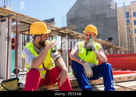 Two young workers drinking a cold beer during break at work Stock Photo