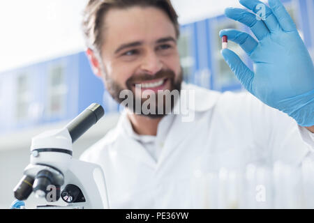 Scientific achievements. Selective focus of new innovative cure being held by nice cheerful positive scientist Stock Photo