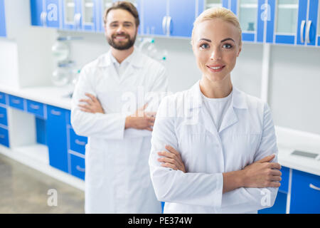 Female researcher. Delighted nice blonde woman standing cross handed and looking at you while standing in the laboratory Stock Photo