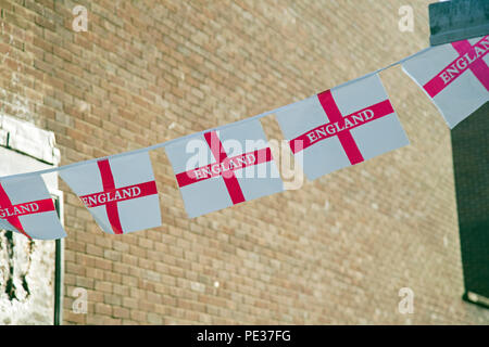 A string of plastic England flags with a deteriorated sign board of a shop behind Stock Photo